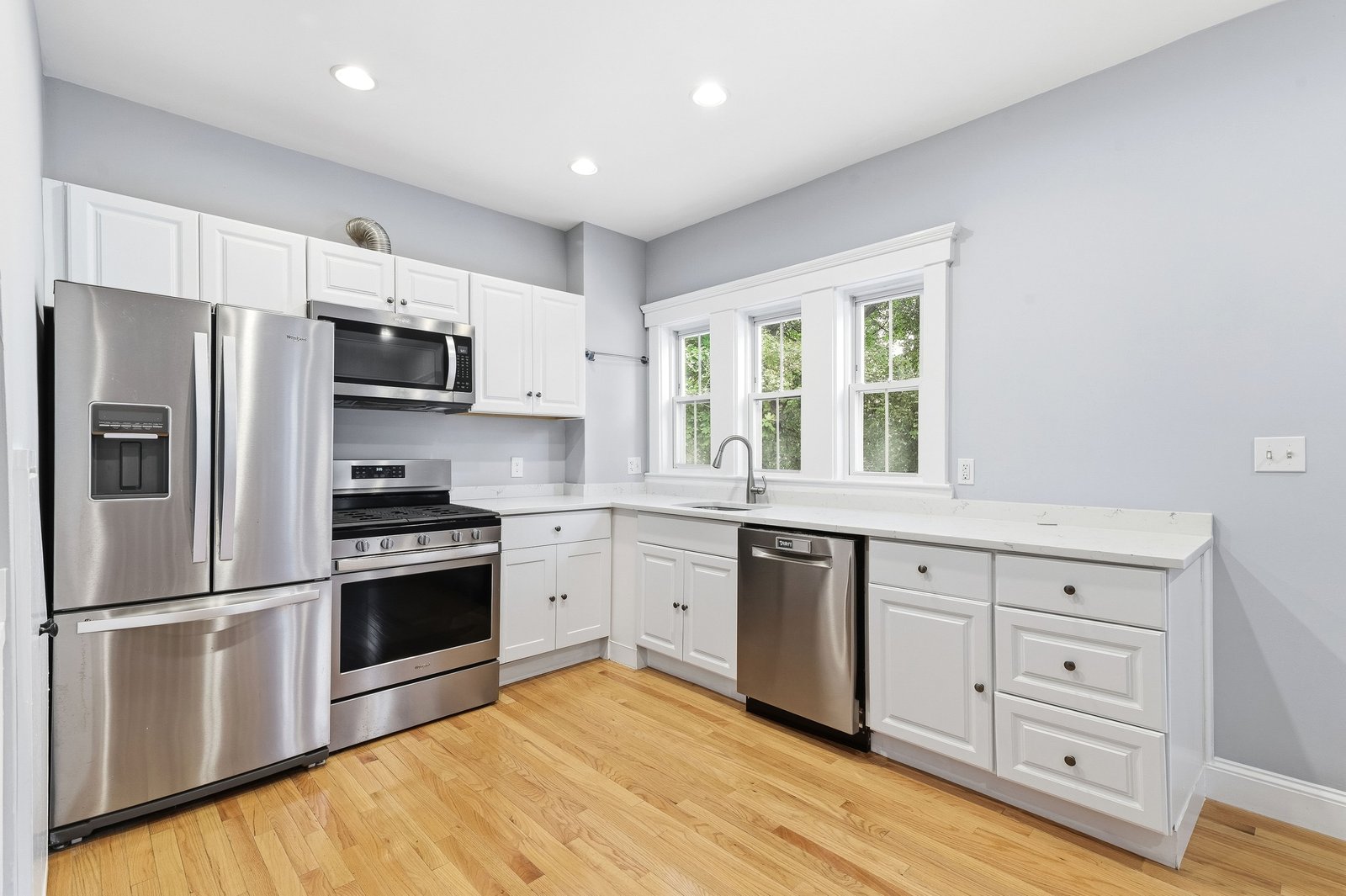 Unit 1 kitchen with white cabinets, quartz counters, and stainless steel appliances